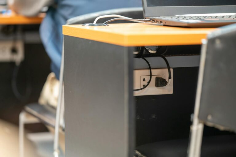 A clean office workspace featuring a desk, laptop, and hidden power cord management.