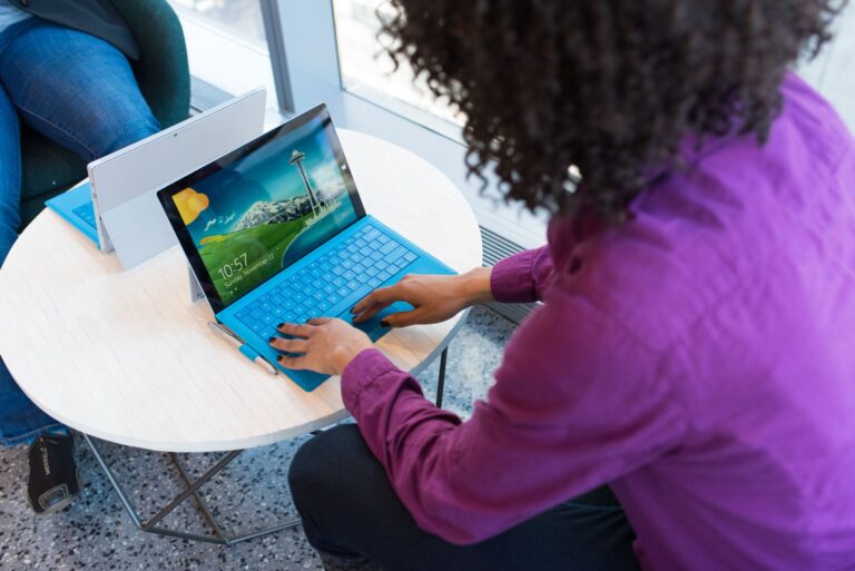 A woman with curly hair working on a laptop in a bright, modern office setting.