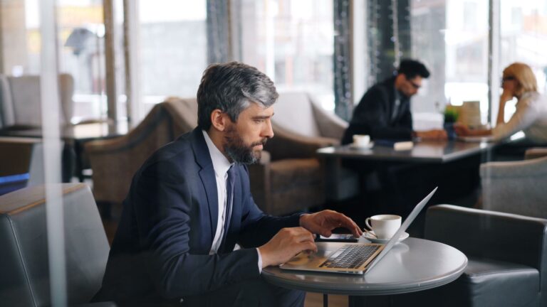 Businessman working on a laptop inside a contemporary café setting, focused and productive.