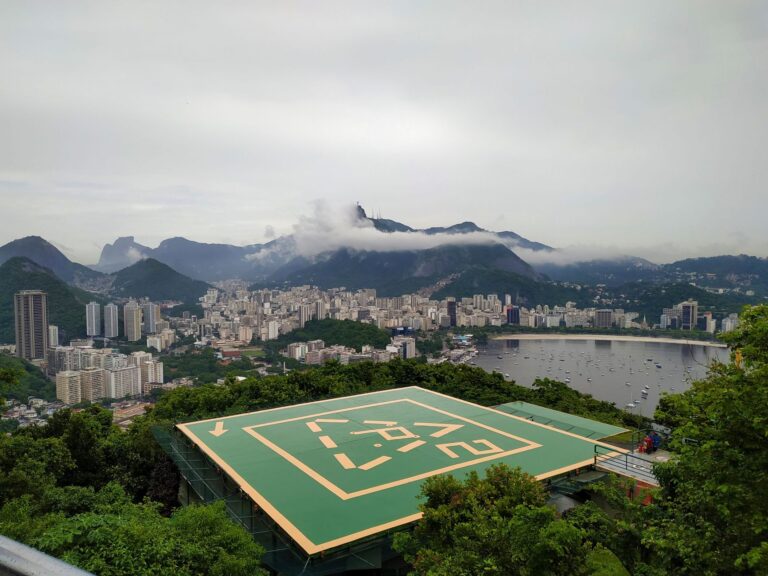 Stunning aerial view of Rio de Janeiro's cityscape with lush greenery and a visible helipad in the foreground.